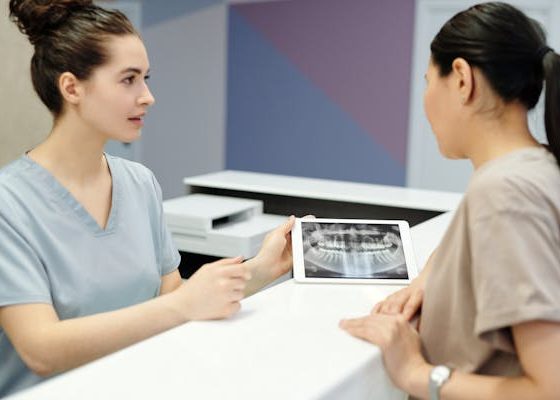 A woman converses with a dental assistant in a clinic setting, discussing dental care and treatment options.